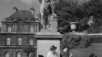 Femmes tricotant au pied d'une statue du jardin du Luxembourg. Paris (6e arr.), 1952.